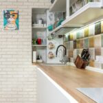 Stylish kitchen counter with various dishware on shelves near sink